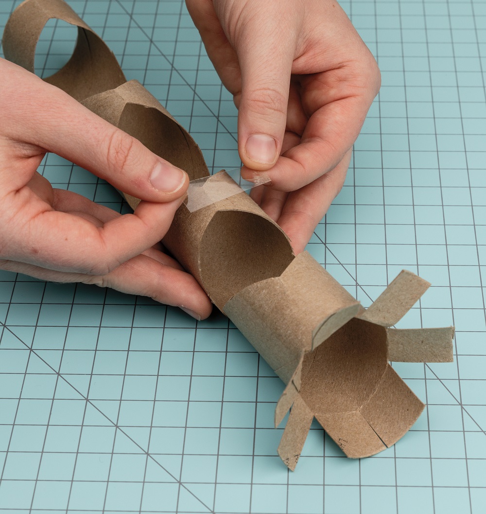 Taping the diamond-shaped holes in the paper towel rolls