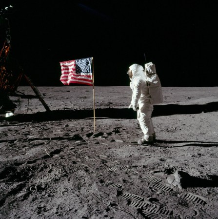 an astronaut stands next to an american flag on the moon