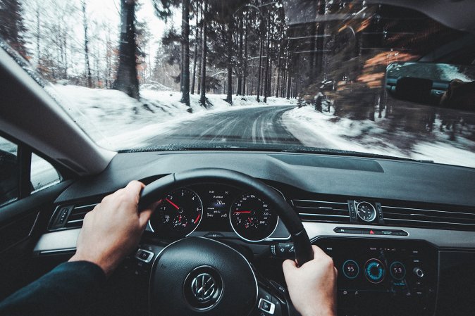 Person driving car down a snowy street with a dash cam.