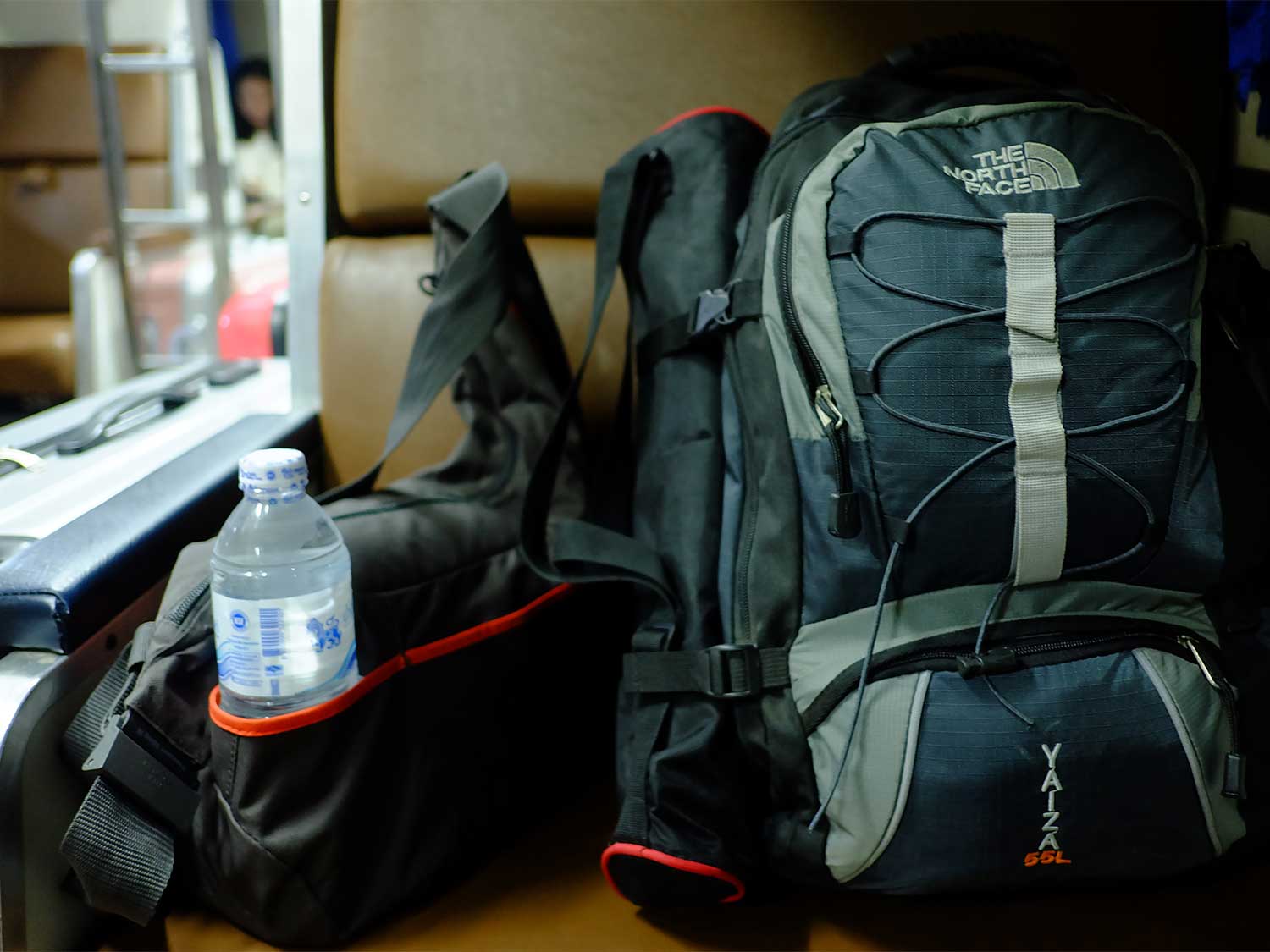 A backpack in a hair next to a water bottle.