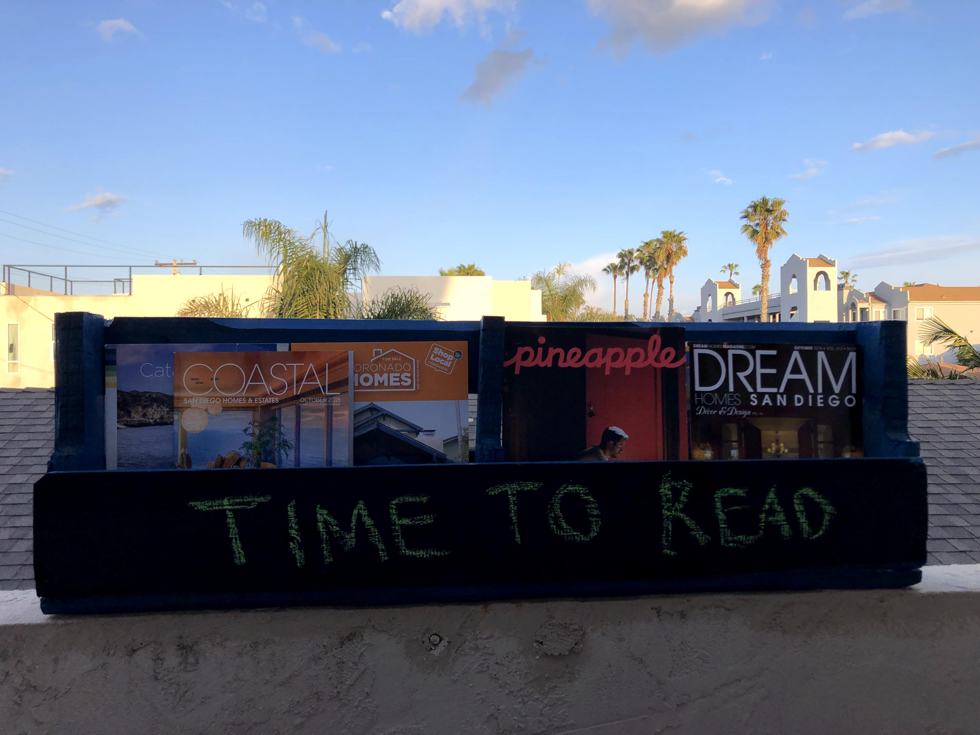 A bookshelf made out of a reclaimed wood pallet, full of books, with a chalkboard panel.