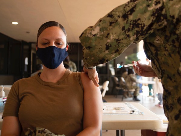 woman with a mask on gets a vaccine