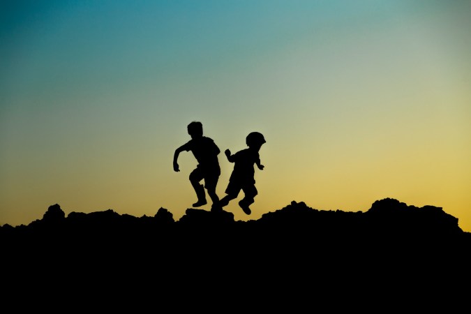 children silhouetted on hill