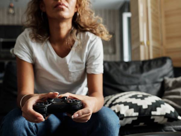 Person playing videogames on a couch with a controller