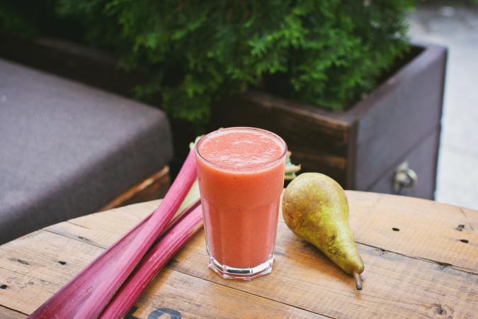 fruits and vegetables on a table next to a glass of colorful liquid for a juice cleanse