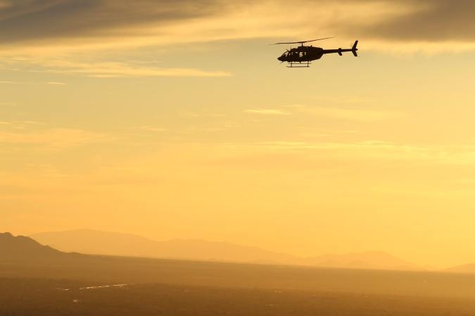 A helicopter flying at sunset.