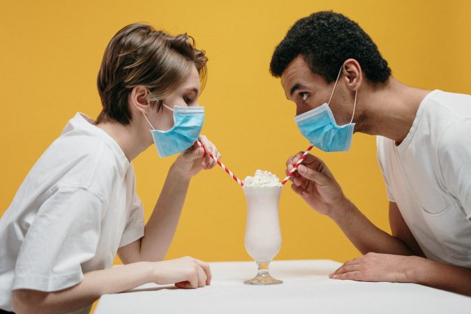 Couple drinking milkshakes with COVID-19 face masks on.