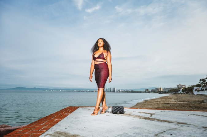 A model in a wine-red cutout dress on a beach