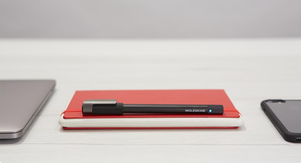 A black Moleskine pen and red tablet notebook that <a href=