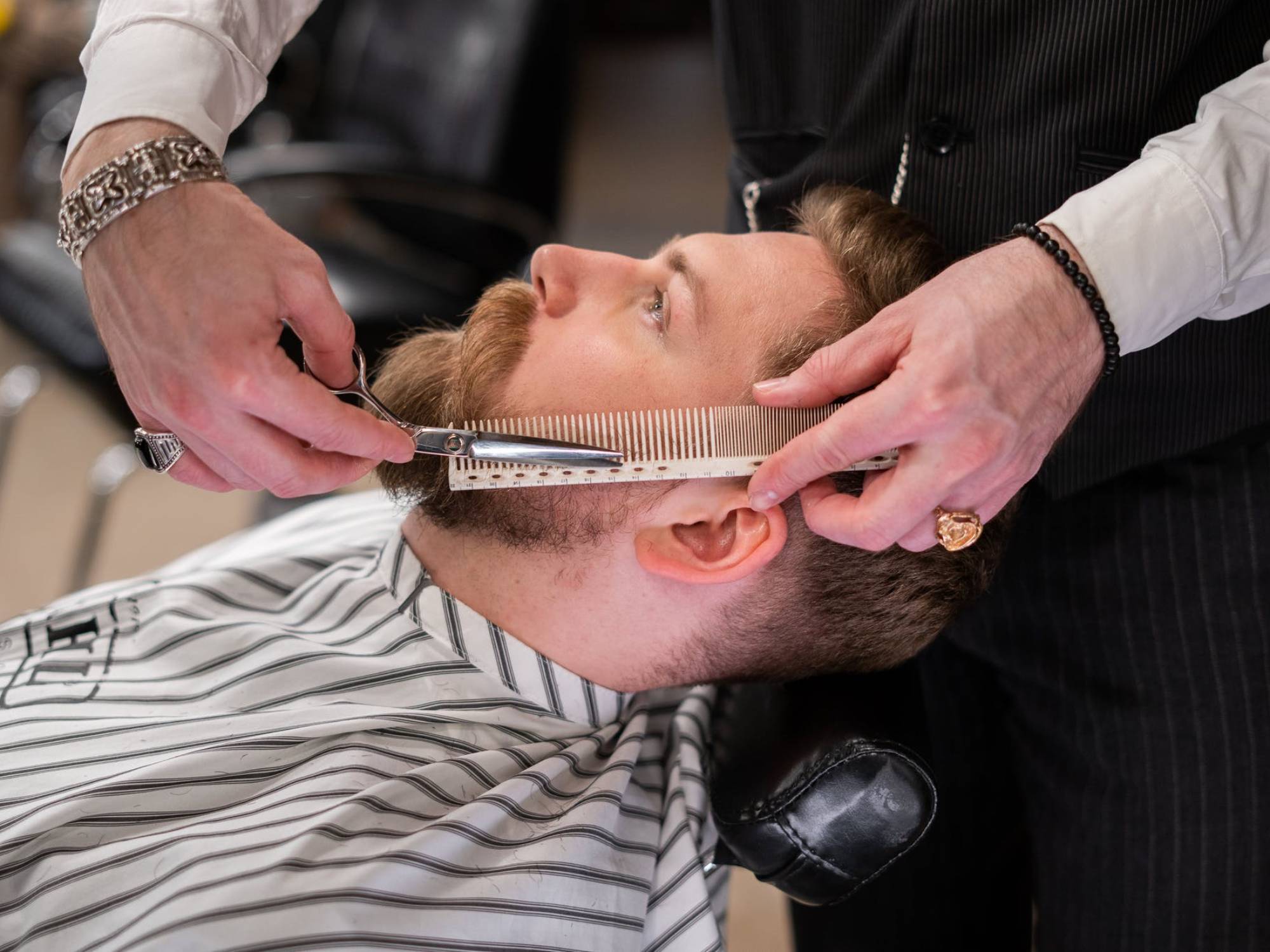 Bearded man at the barber shop getting his beard trimmed