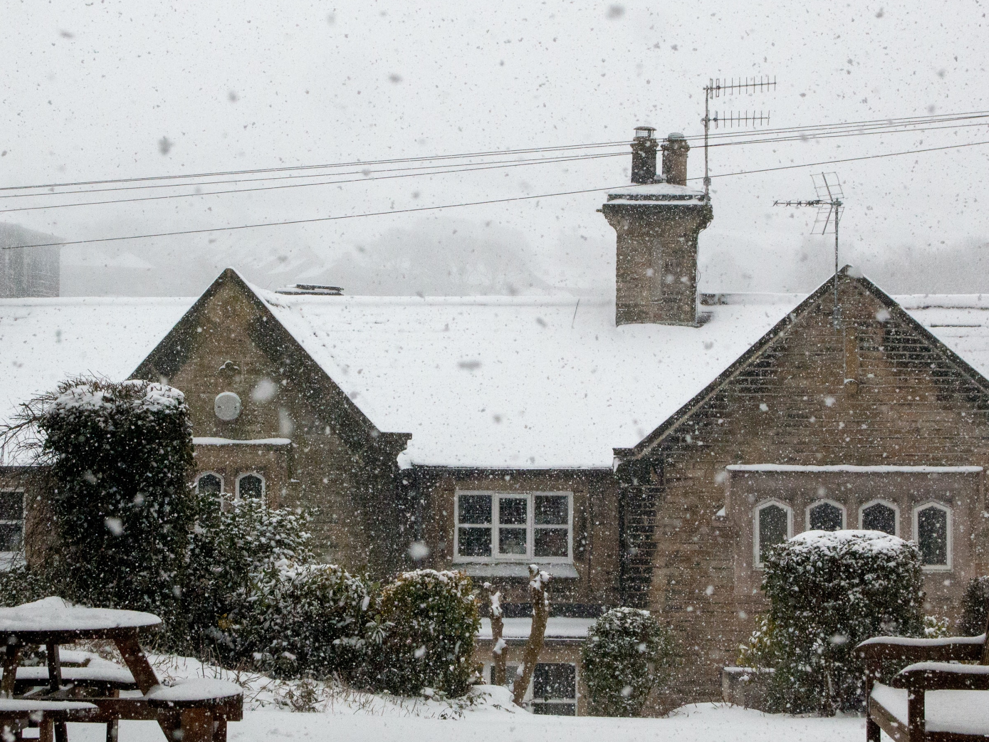 A stone building under power lines during a snowstorm.