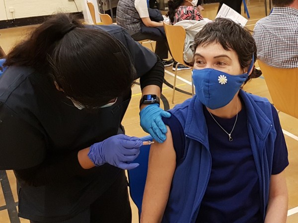 someone getting a COVID-19 vaccine with a mask on.