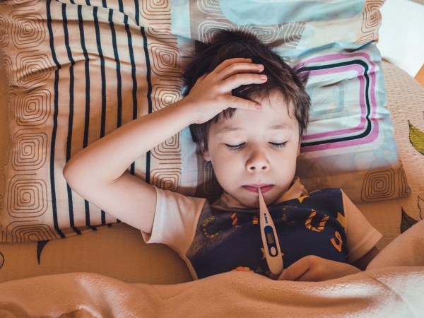 sick little boy with thermometer in his mouth