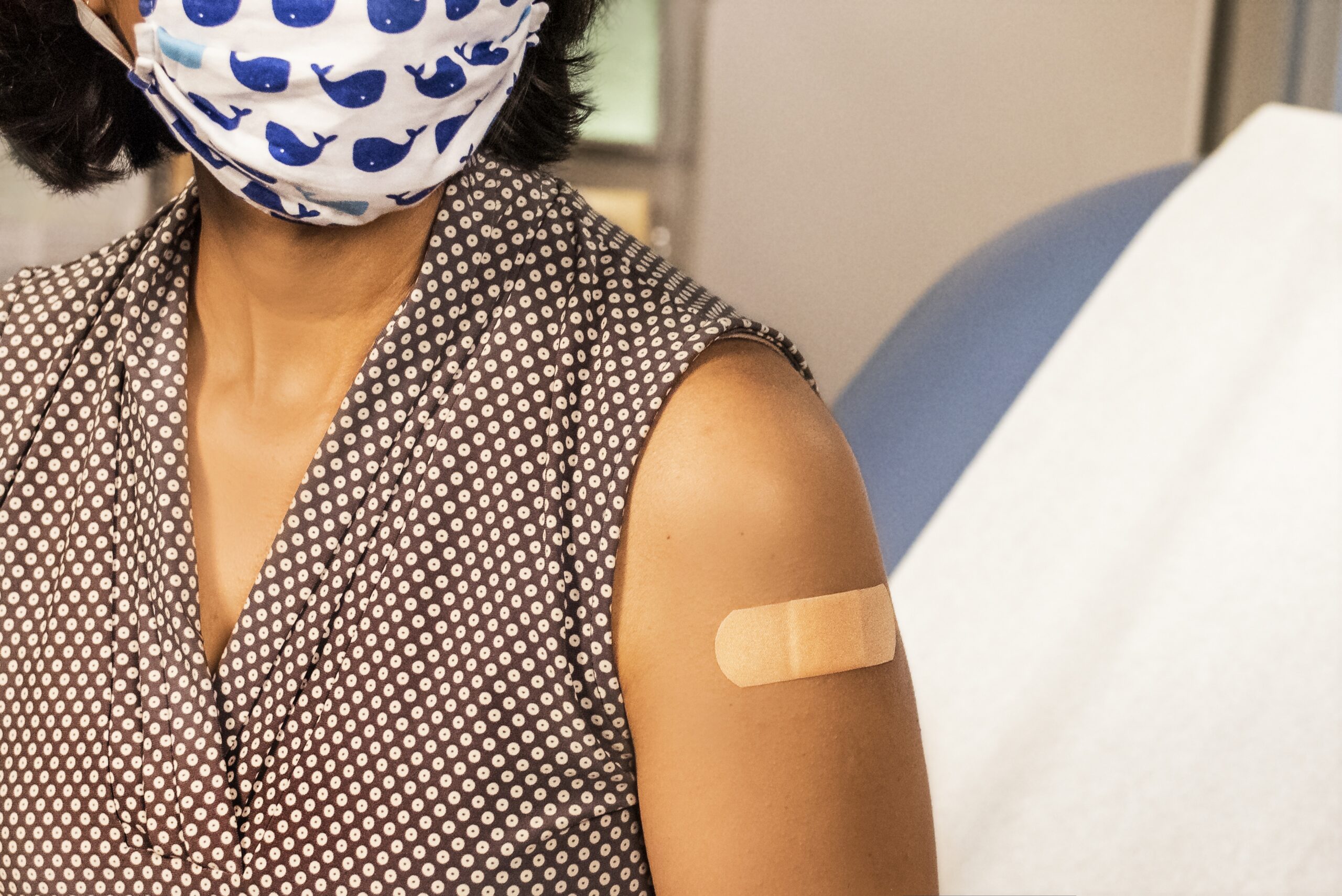 Woman wearing mask in doctor's office after receiving COVID-19 vaccine.