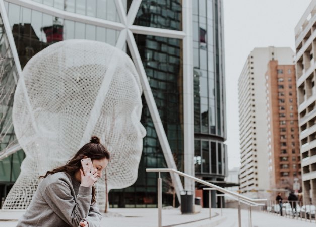 Person with long brown hour talking on iPhone in front of statue