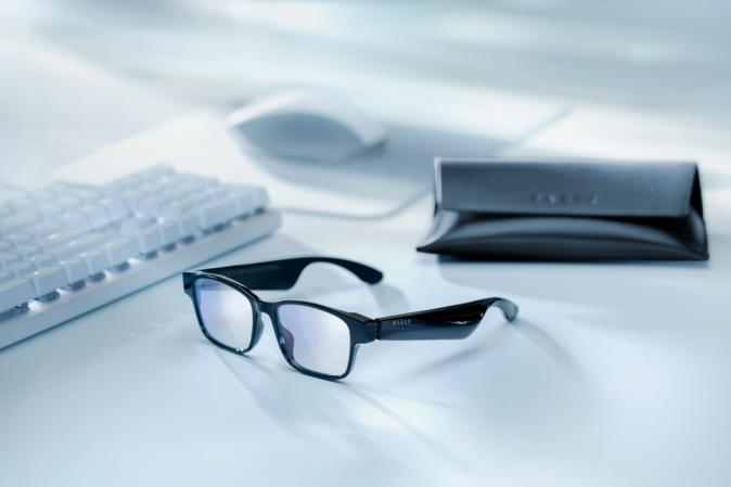 Razer Anzu Smart Glasses sitting on a desk with accessories.