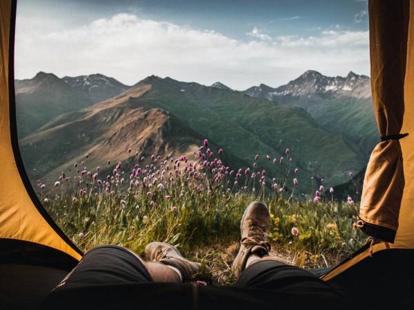 Person camping in the outdoors with feet out of tent.