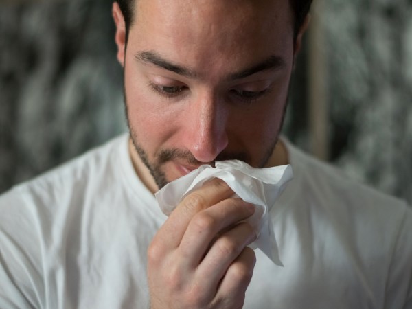 man wiping his nose with a tissue