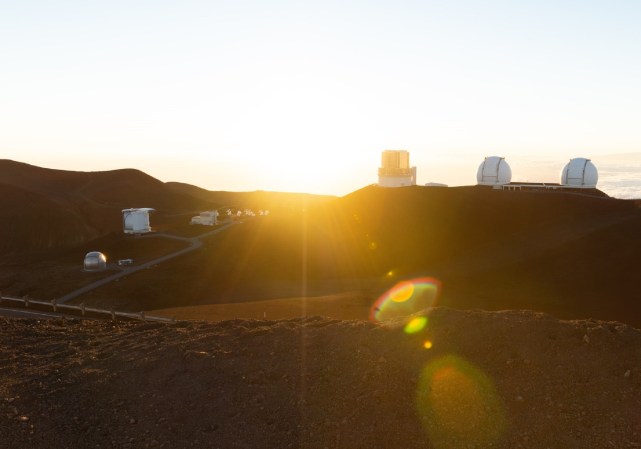 The sun over Maunakea volcano and research observatories in Hawaii