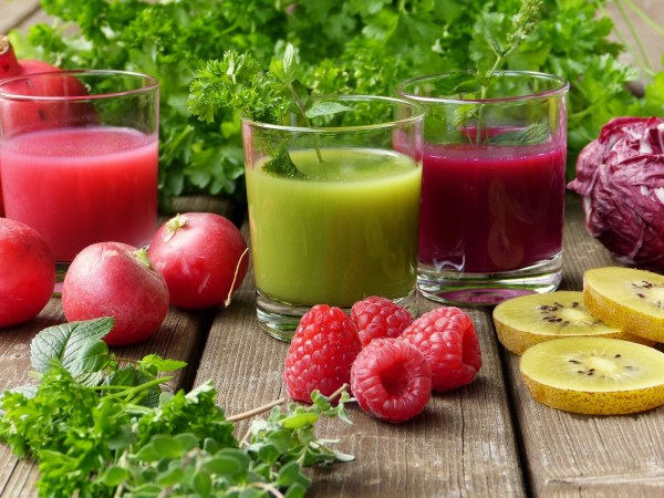 Glasses of juice, smoothies, and berries on a table.