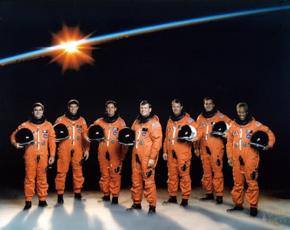 The NASA STS-39 shuttle crew in orange astronaut suits on a space backdrop