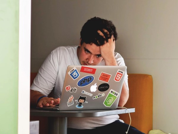 A man sitting in a cubicle, frustrated with a slow computer. He's probably wondering, "Why is my computer so slow?"