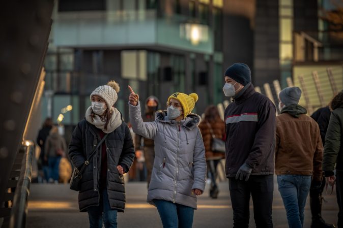 people wearing masks walking down a street