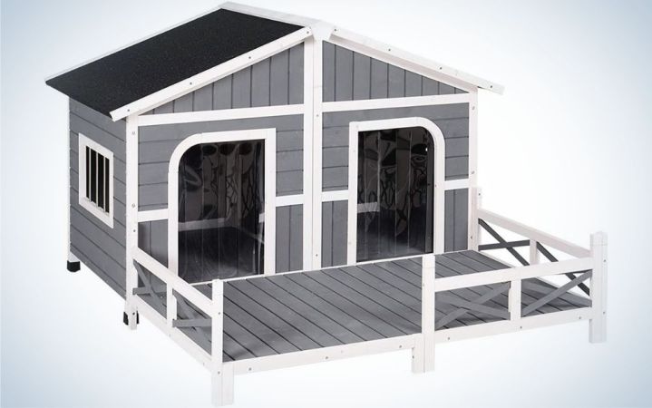  A grey with black roof wooden outdoor dog house with two doors in it.