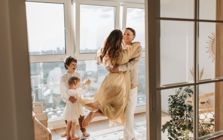 A happy family hugging each other and wearing beige and white clothes.