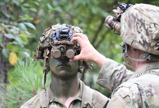 Two Army service members in camo testing night vision goggles