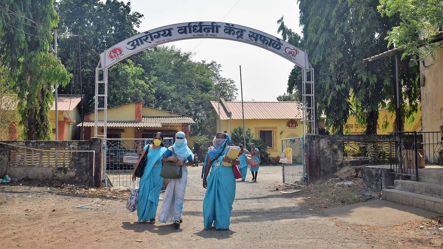 Saphale health center entrance with people in blue saris and masks walking out