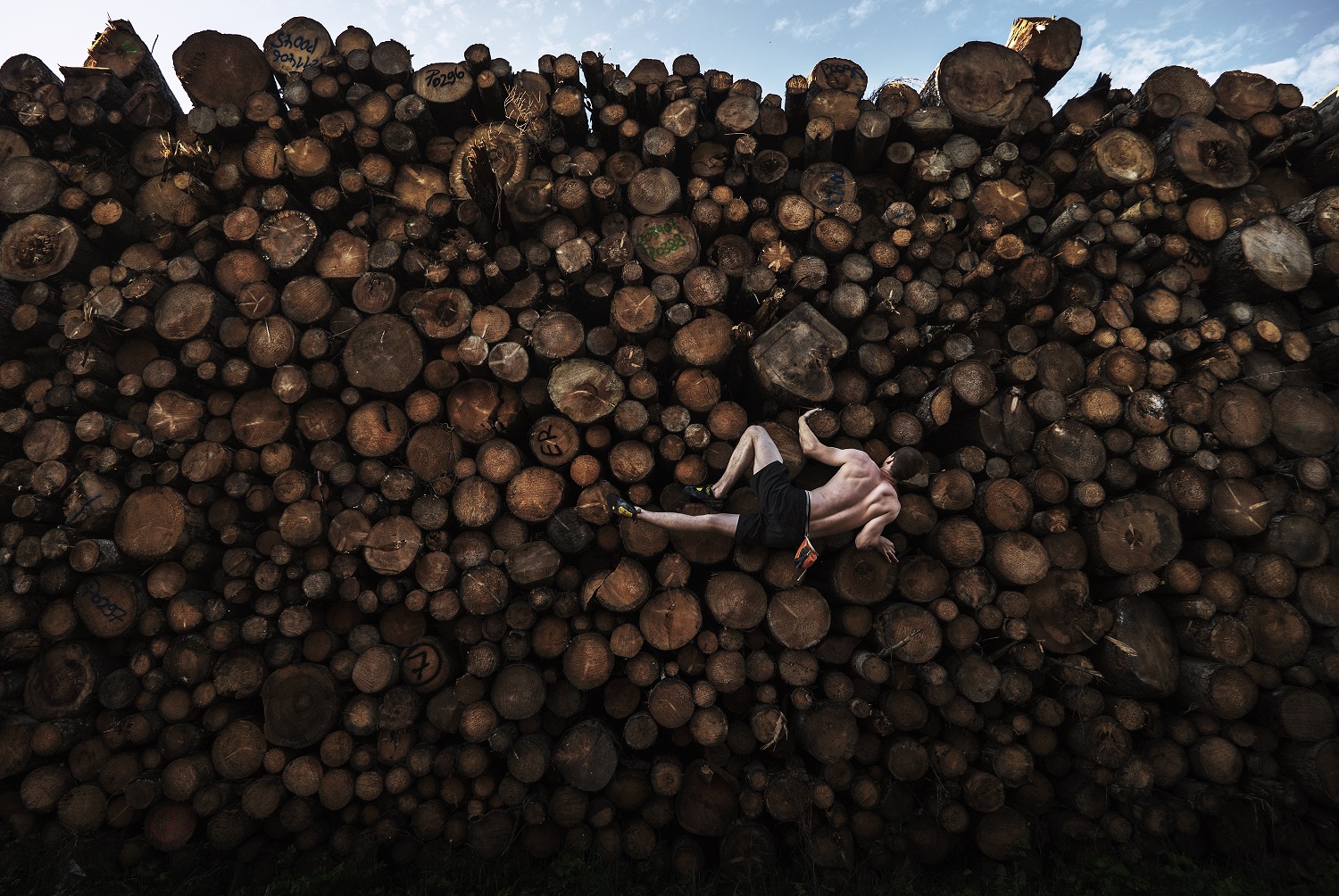 Shirtless rock climber on a stack of lumber