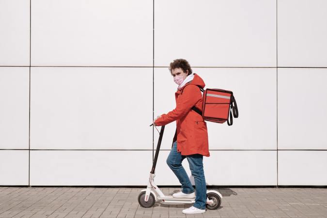 A person wearing a mask rides a scooter