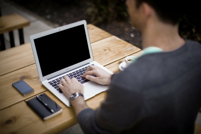 A person using a laptop on a wooden desk