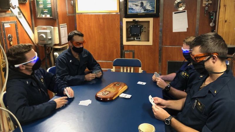 Sailors playing cards in orange and blue-light goggles