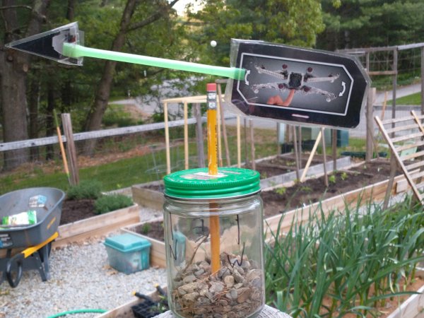 A DIY weather vane made out of recycled materials, set up outside.