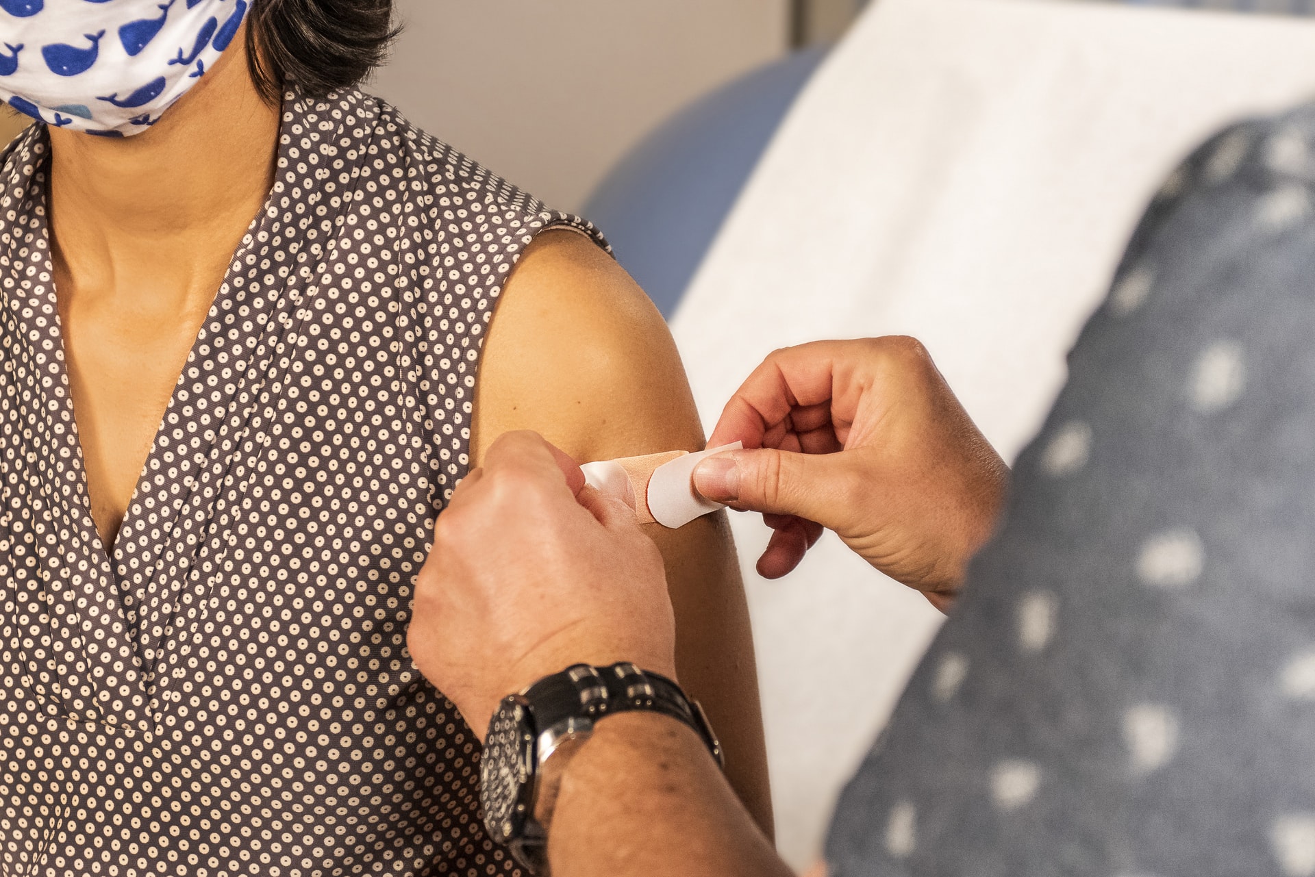 A doctor puts a bandage on a woman's arm.