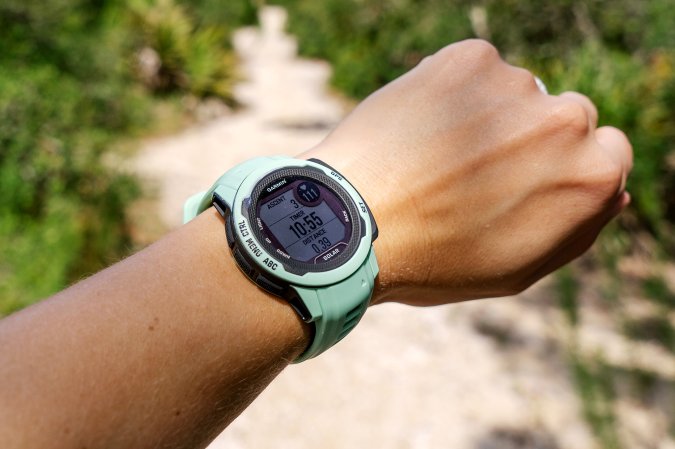 Neo Tropic Garmin Instinct 2S Solar on Abby's wrist on a sandy trail