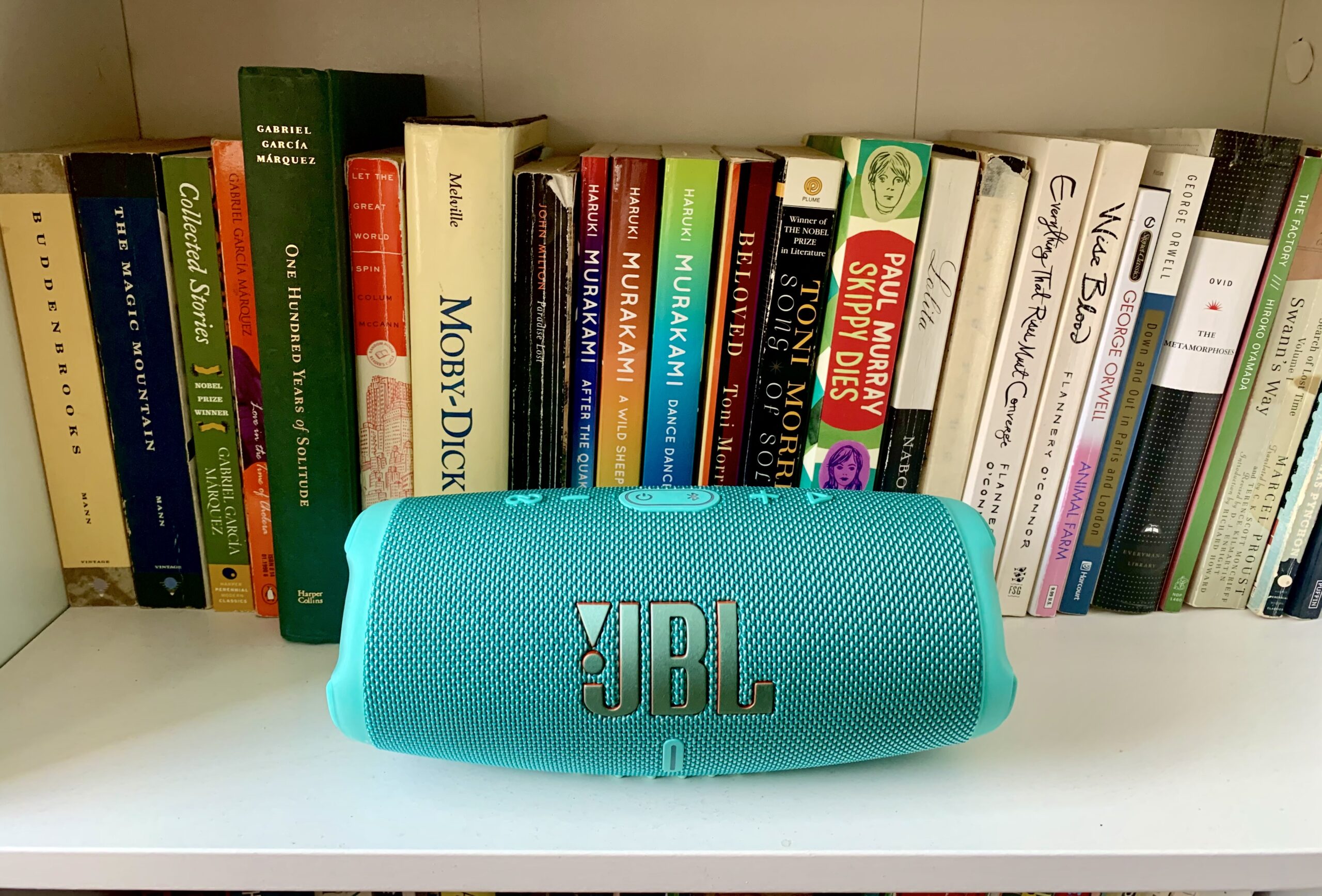 JBL Charge 5 in teal on a bookshelf