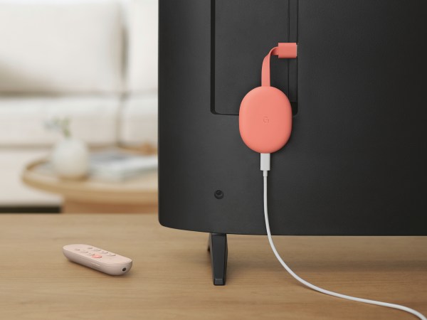 Pink Chromecast dangling from a Tv