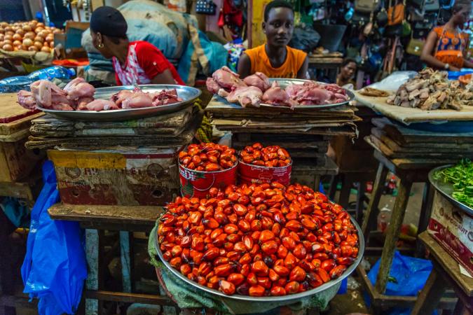 Red palm oil fruits in a basket at an outdoor market