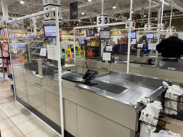 Plexiglass barriers shield cashier stations in grocery store checkout lanes.