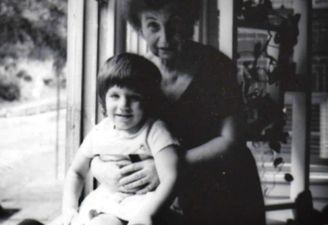 Toddler with grandmother near window in black and white photo