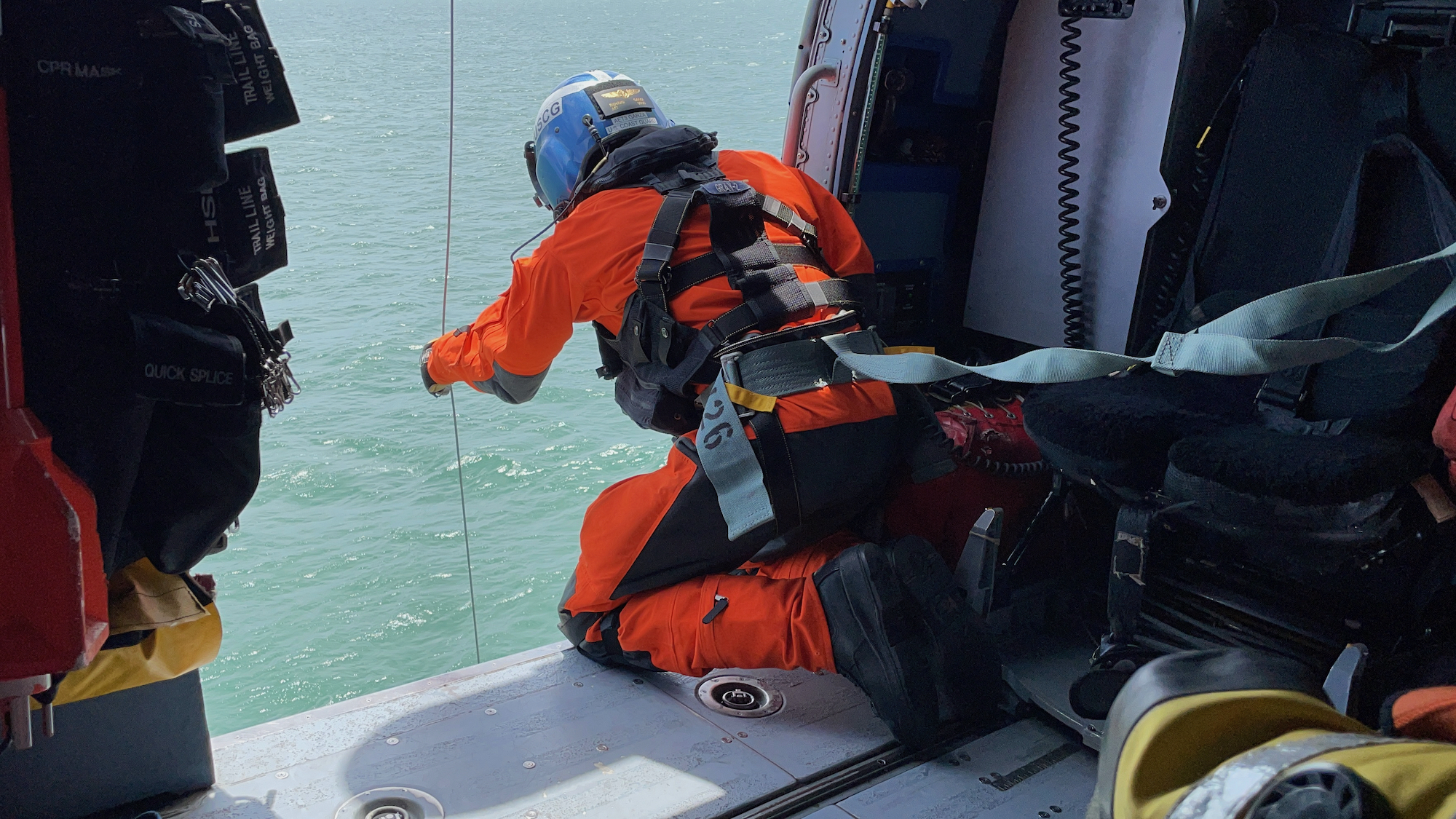 A member of the Coast Guard at the door of a helicopter