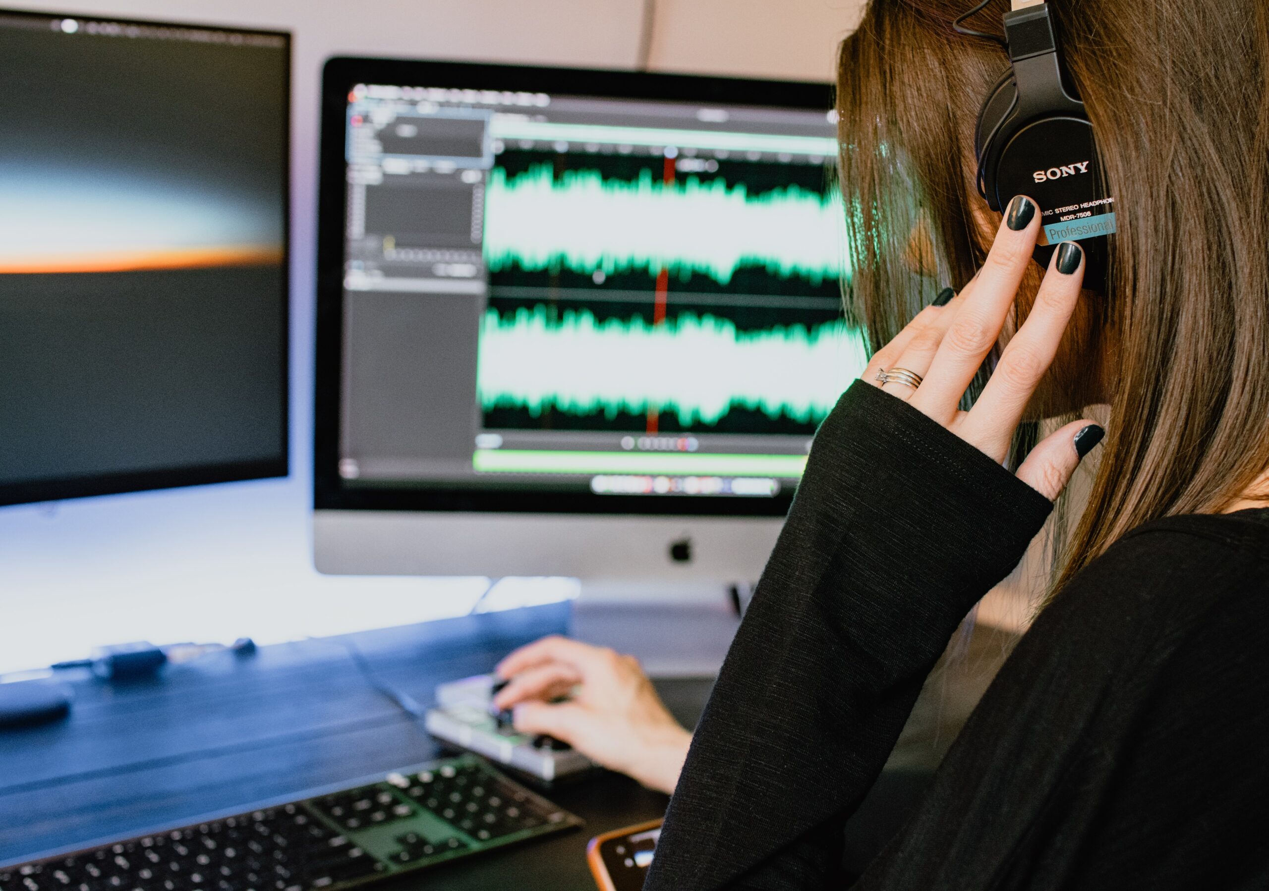 Woman wearing Sony 7506 headphones at computer