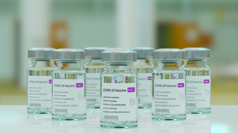 Several glass vials of the COVID-19 vaccine sit on a table top.