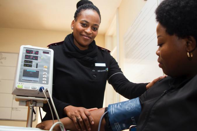 Black health care worker reading blood pressure on Black patient