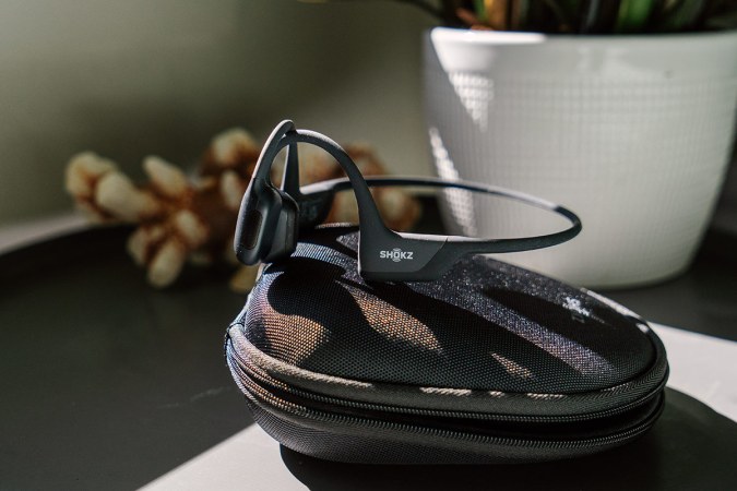  A pair of Shokz OpenRun Pro bone-conduction headphones rest on their case on an end table.