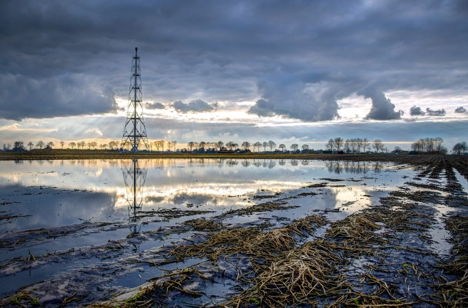 Marsh with fossil fuel facility and powerlines in distance