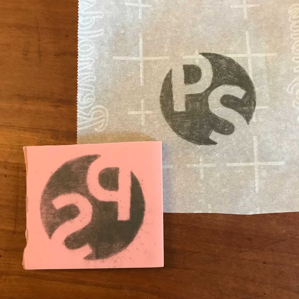 The first stage of a homemade rubber stamp, with a pencil drawing of the design and its mirror image on the rubber block.